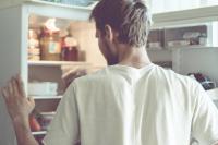 man looks into open refrigerator
